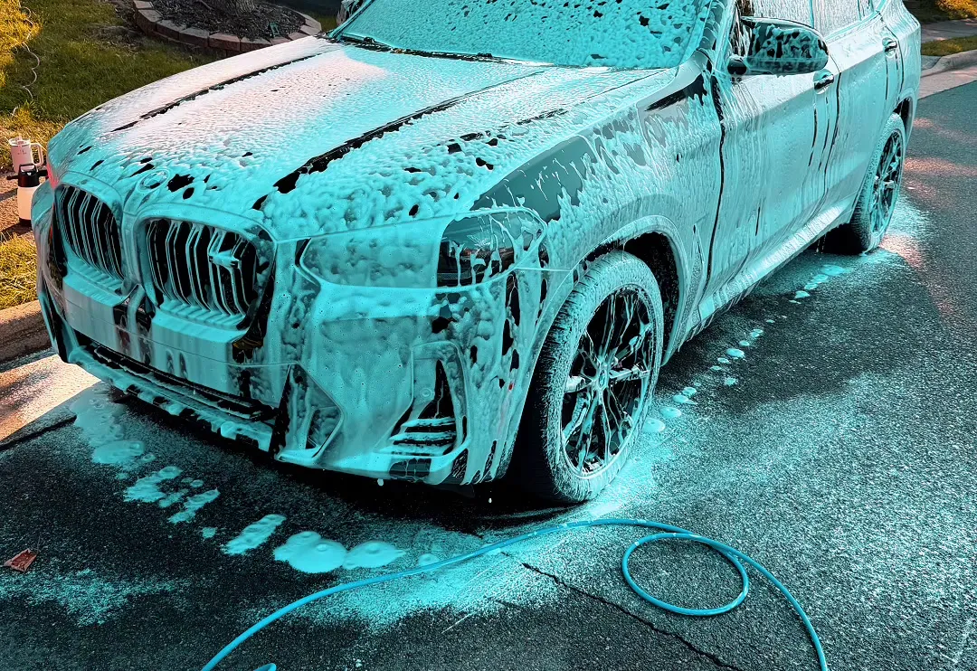 Black BMW X3 covered in thick pre-wash foam during a Max Crew exterior detail